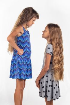 Two girls of different stature, one of them stood on a chair to be taller than the other
