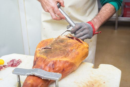Close up of worker hands in the industrial process of cutting iberian ham