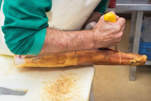 Close up of worker hands in the industrial process of cutting iberian ham