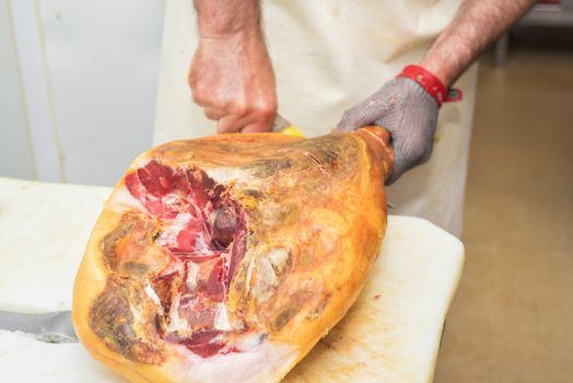 Close up of worker hands in the industrial process of cutting iberian ham