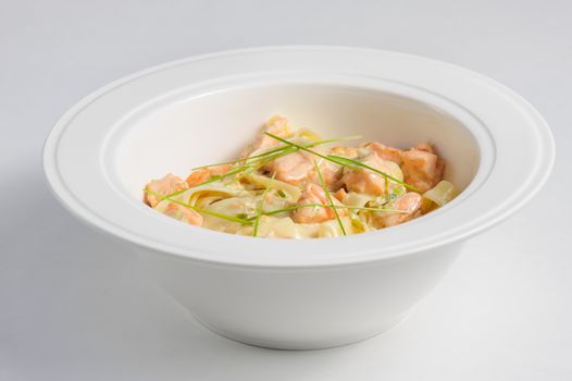 Fettuccine with salmon at white plate and background