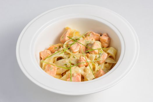 Fettuccine with salmon at white plate and background