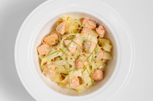 Fettuccine with salmon at white plate, top view