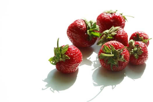 Few strawberry fruits on white against morning sun light