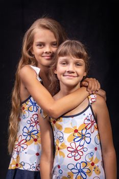 Portrait of two friendly sisters on a black background