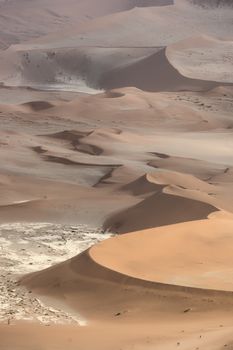 People walking in the beautiful orange and red-brown sand dunes near Deadvlei in the Namib-Naukluft National Park, Namibia