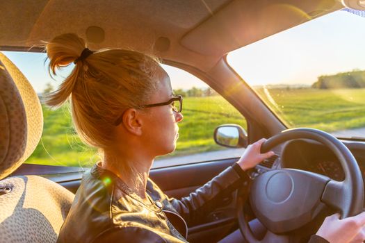 Casual caucasian woman driving a passenger car for a journey in countryside.