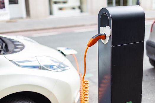 Power supply for electric car charging. Electric car charging station. Close up of the power supply plugged into an electric car being charged.