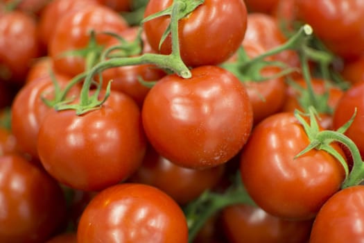 Red tomatoes sold at the market. It looks very fresh. The stalks are still green