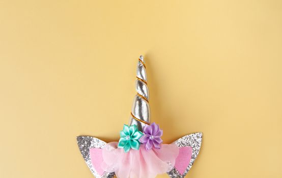 Halloween party accessory, rim with ears and unicorn horn. Pastel yellow background, copy space. Holiday flat lay. Minimal style. Horizontal