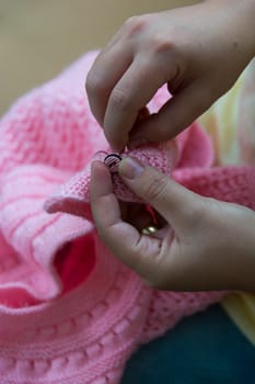 a woman stitch a child's clothe. hand work, button sewing