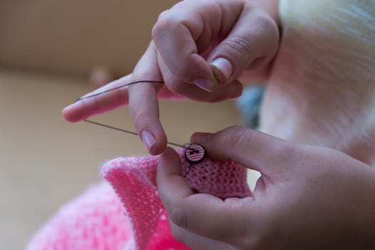 a woman stitch a child's clothe. hand work, button sewing