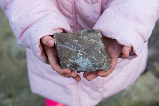 Little girl holds a stone in the cold with her little hands