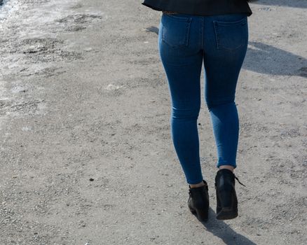 The woman is walking on the street. dressed in jeans.she has a sexy buttock
