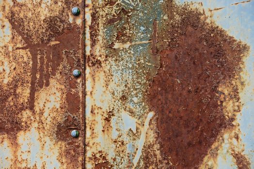 Grunge texture: rusty metal surface covered with blue paint flaking and cracking texture, with seam and rivets