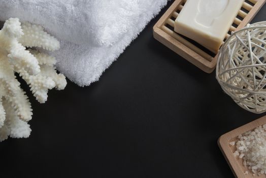 Cleansing spa accessories with sea salt, soap, white towel, and coral, isolated on a black background