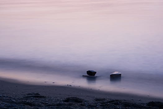 the sea has become silky. two rocks on the sea surface