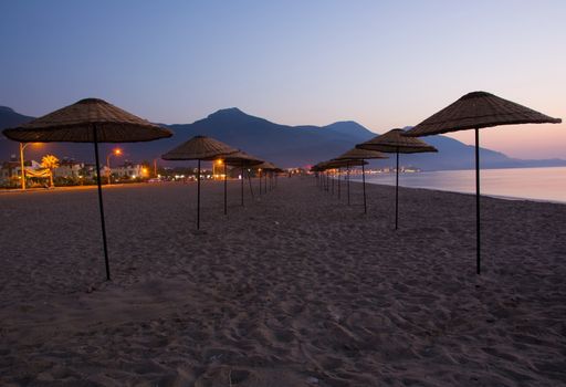 On the beach, lined, sun umbrella. like a road.