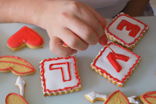 women in the kitchen prepare for the Valentine's Day. woman prepares Valentine's Day cookie. adorns heart shapes with his hands. ornamentation and shaping