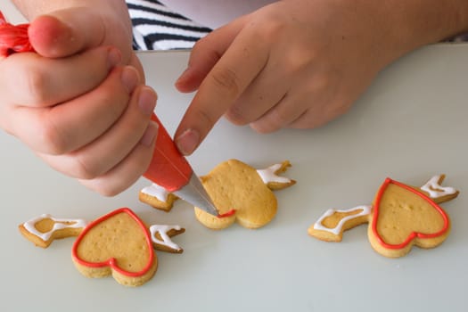 women in the kitchen prepare for the Valentine's Day. woman prepares Valentine's Day cookie. adorns heart shapes with his hands. ornamentation and shaping