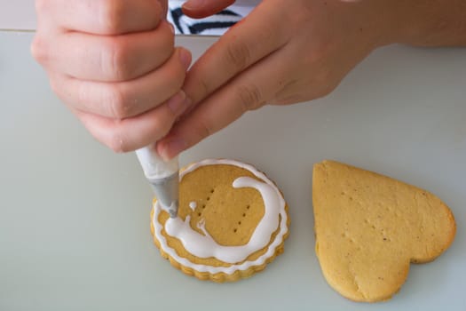 women in the kitchen prepare for the Valentine's Day. woman prepares Valentine's Day cookie. adorns heart shapes with his hands.ornamentation and shaping