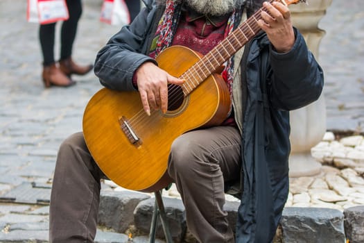 The street artist plays the guitar. making money with street music. Fingerstyle