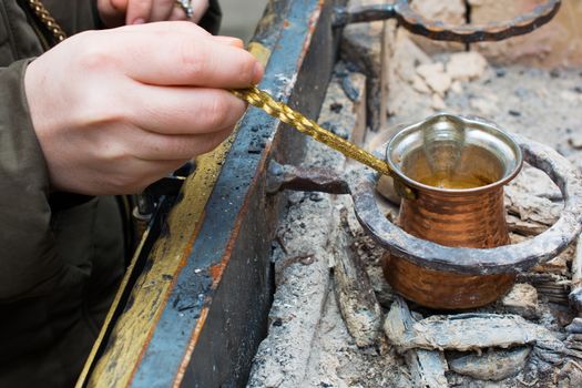 woman cooks Turkish coffee in barbecue. pleasant and abundantly frothy