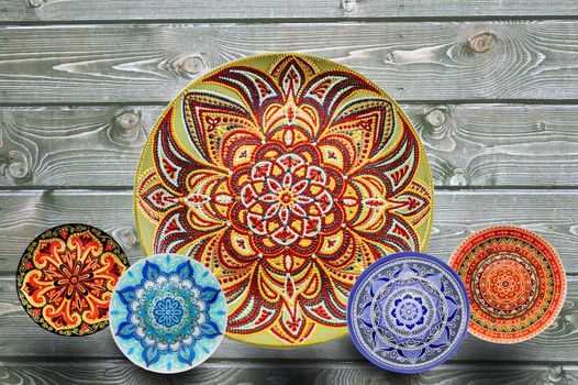 Set of decorative ceramic plates hand painted dot pattern with acrylic paints on a gray wooden background. Copy space