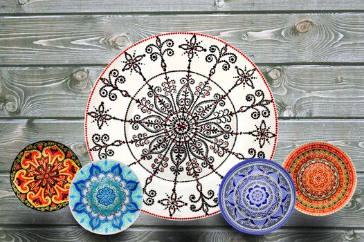 Set of decorative ceramic plates hand painted dot pattern with acrylic paints on a gray wooden background. Copy space