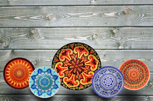 Set of decorative ceramic plates hand painted dot pattern with acrylic paints on a gray wooden background. Copy space