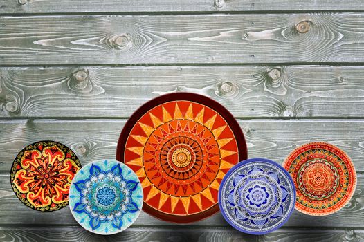 Set of decorative ceramic plates hand painted dot pattern with acrylic paints on a gray wooden background. Copy space