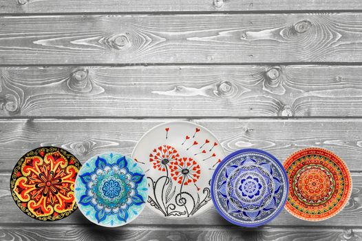 Set of decorative ceramic plates hand painted dot pattern with acrylic paints on a gray wooden background. Copy space