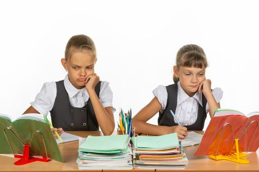 Sad schoolgirls look at a book in a lesson