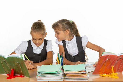 Girl looks at what her desk neighbor writes in a notebook