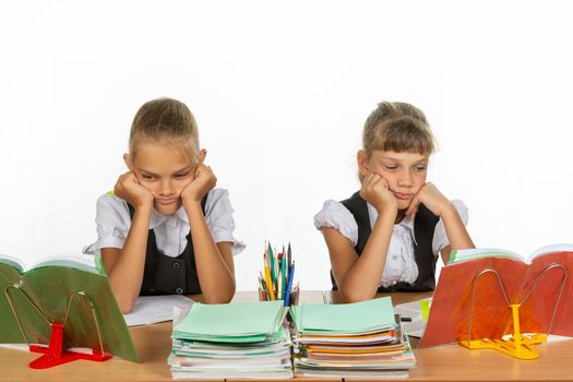 Sad schoolgirls look at textbooks in class