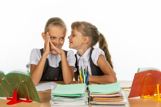 Girlfriend at school desk tells something interesting on the ear