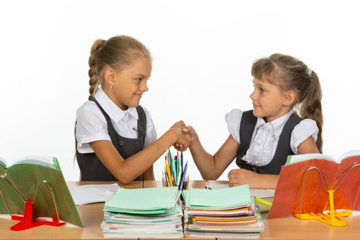 Two girls at a desk shake hands