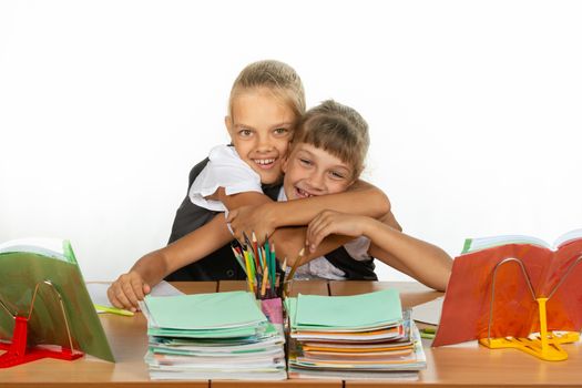 Two schoolgirls are sitting at a desk looking at textbooks