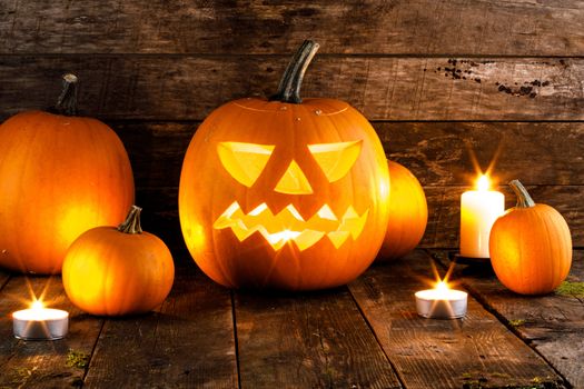 Halloween pumpkin head jack o lantern and candles on wooden background