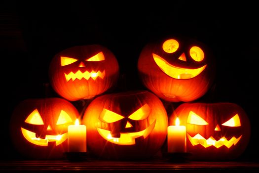 Halloween pumpkin head jack o lantern and candles on wooden background