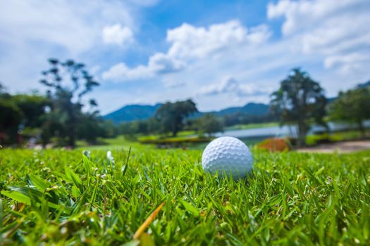 Golf ball on course, beautiful landscape with lake and mountains on background