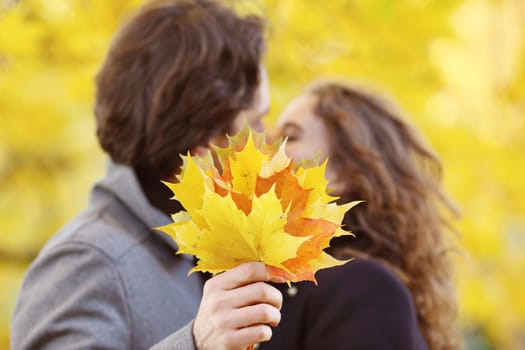 love, relationship, family and people concept - couple with maple leaves kissing in autumn park