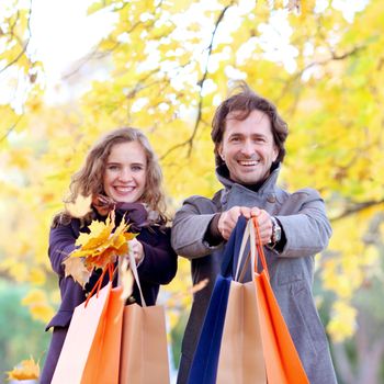 Couple with shopping paper bags in fall forest , autumn sale concept