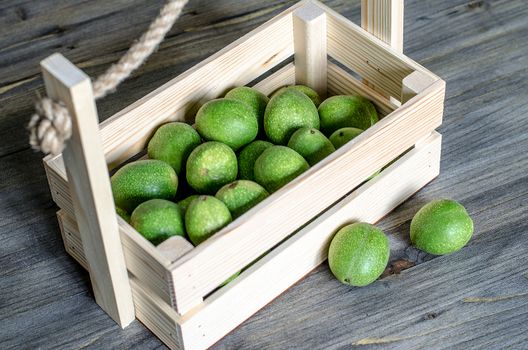 Young fruits of walnuts in a green shell in a wooden box