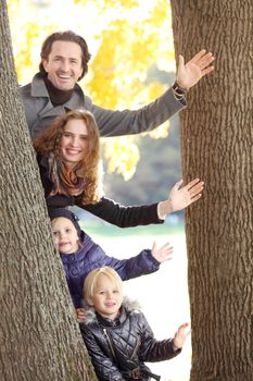 Happy family of parents and children waving hands greeting in autumn park