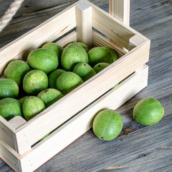 Young fruits of walnuts in a green shell in a wooden box