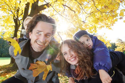 Happy smiling family of parents and children having fun hugging in autumn park