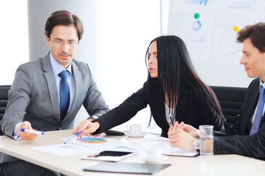 Workers at business meeting looking at presentation of financial reports in modern office