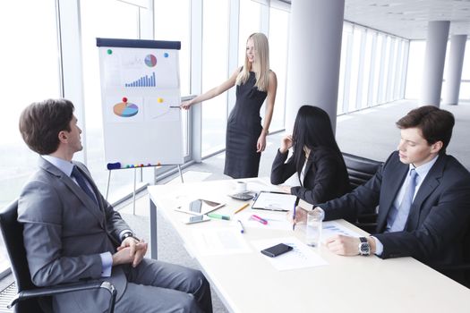 Workers at business meeting looking at presentation of financial reports in modern office