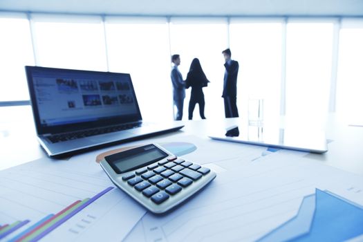Financial reports, calculator and laptop on table in office
